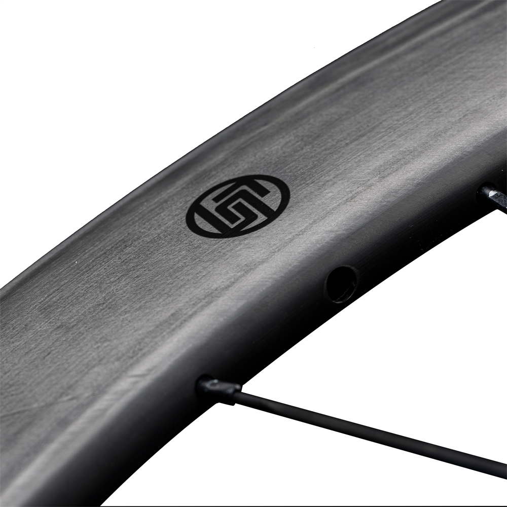 Lún Routte matte carbon fiber wheel close-up showing black Lún logo and spoke detail.