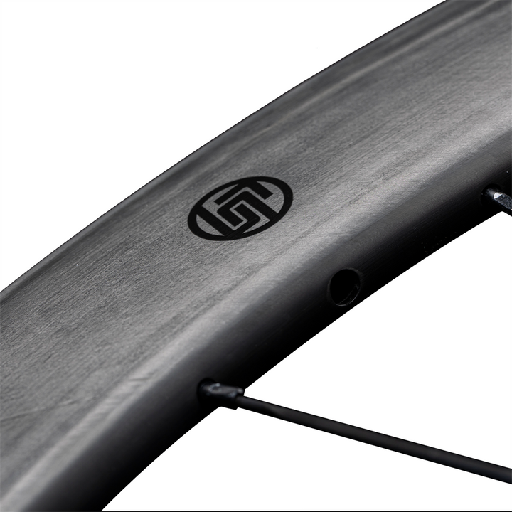 Lún Routte matte carbon fiber wheel close-up showing black Lún logo and spoke detail.