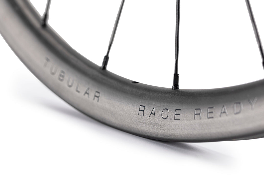Lún Road TD30 tubular disc brake wheel, grey carbon rim with TUBULAR & RACE READY text, black spokes.