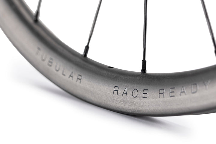 Lún Road TD30 tubular disc brake wheel, grey carbon rim with TUBULAR & RACE READY text, black spokes.