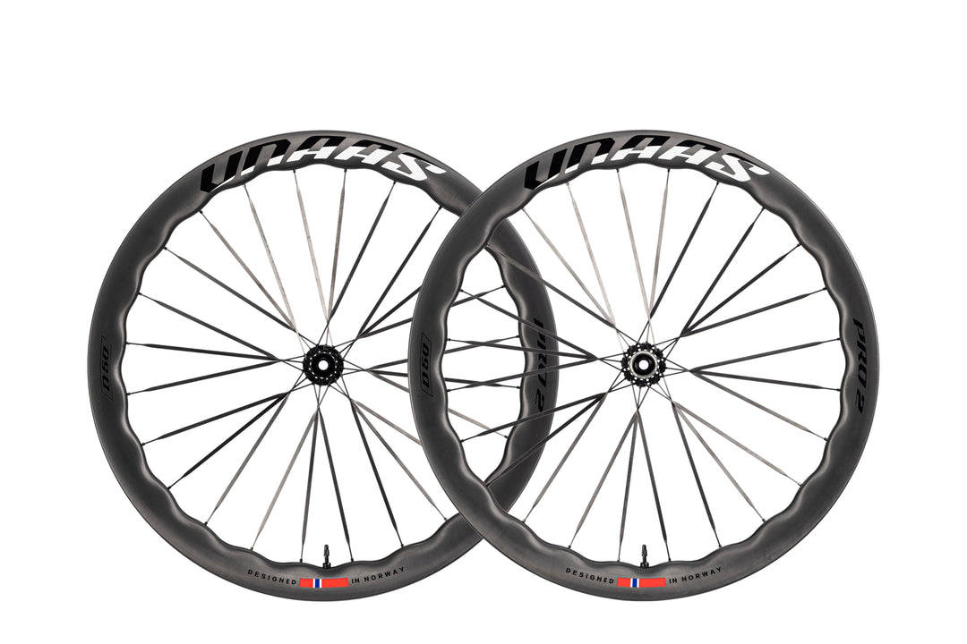Two UNAAS Pro2 Wave carbon bicycle wheels with wave rims and white branding, designed in Norway.