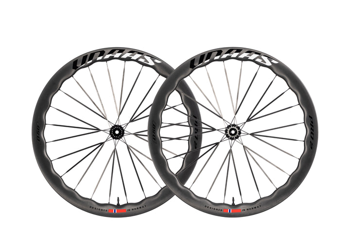 Two UNAAS Pro2 Wave carbon bicycle wheels with wave rims and white branding, designed in Norway.
