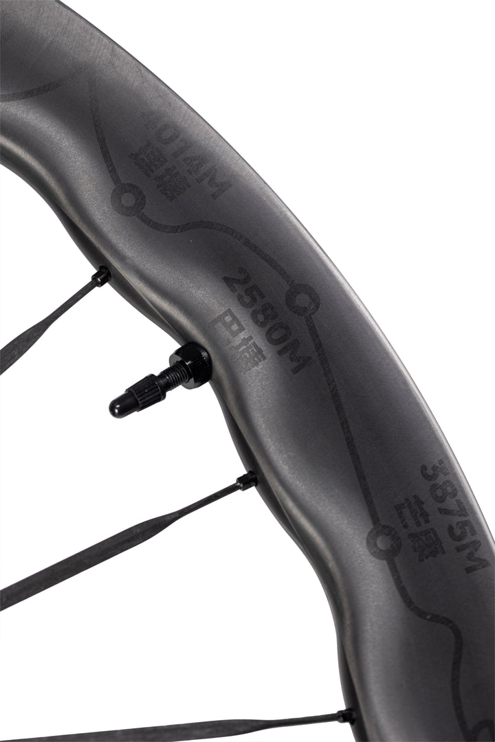UNAAS Pro2 matte black carbon wheel rim with wave design, "014M", "2580M", "3875M" text, and route graphic.