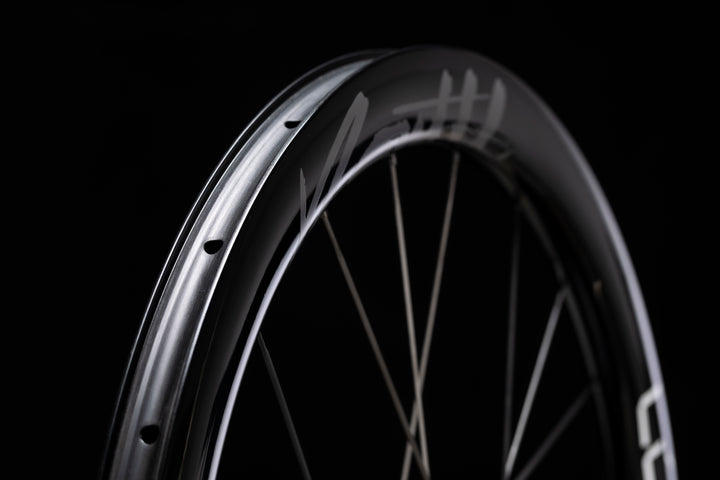 Lún Routte 3 carbon fiber bicycle wheel, glossy black with silver branding and spokes, showcasing product appearance.