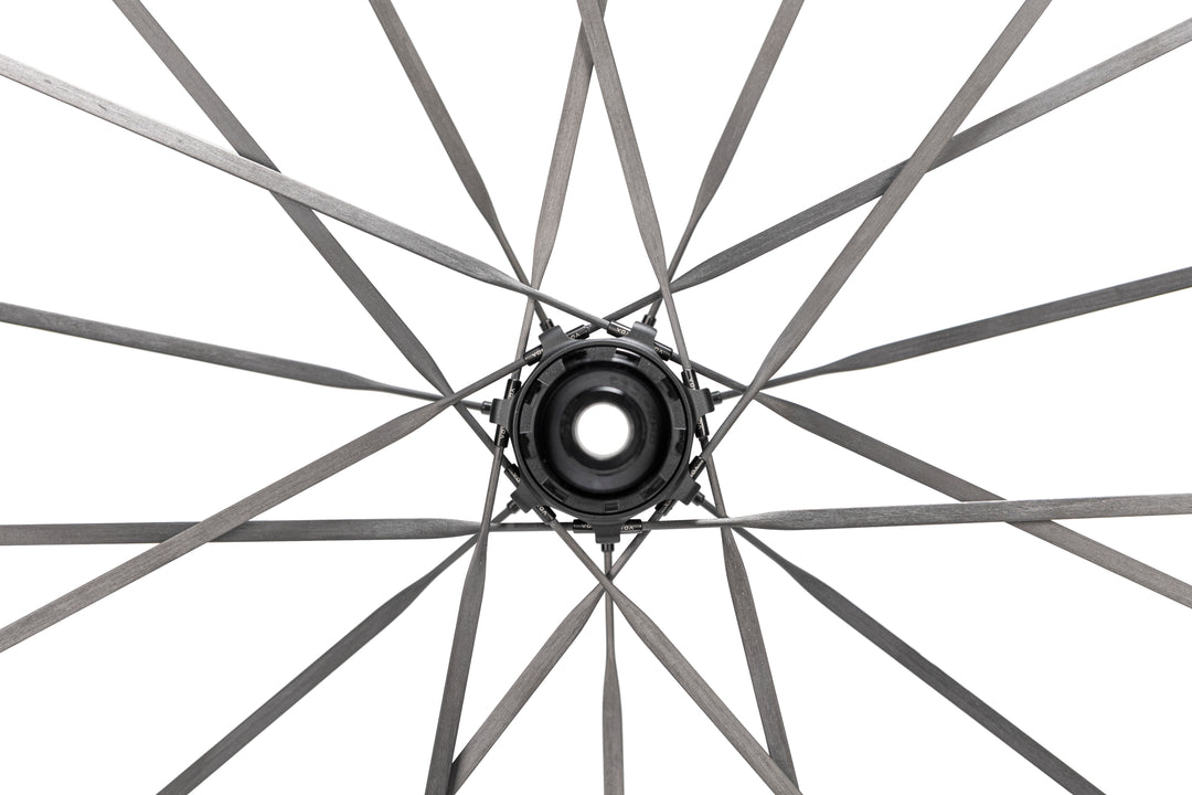 Close-up of HYPER 5 bicycle wheel hub with RATCHET SMN V1 freehub and flat dark grey carbon fiber spokes.
