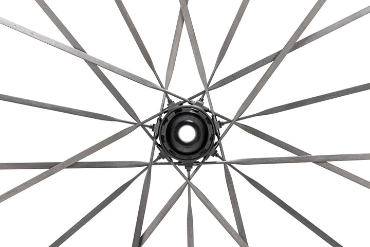 Close-up of HYPER 5 bicycle wheel hub with RATCHET SMN V1 freehub and flat dark grey carbon fiber spokes.