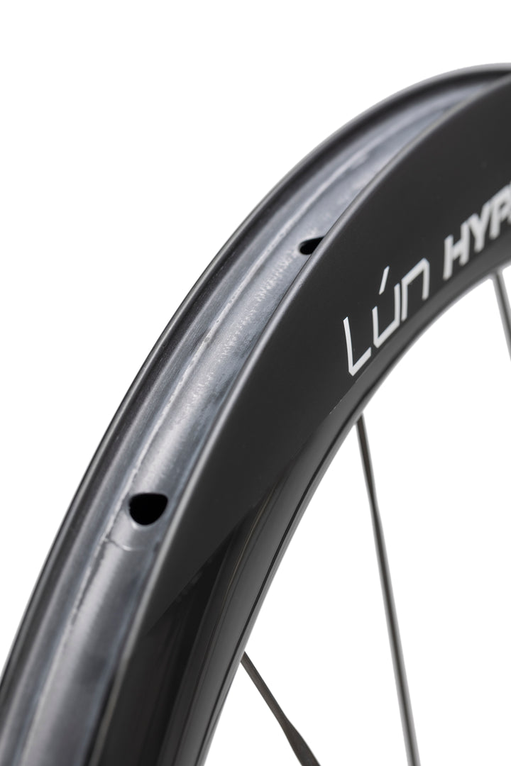 Close-up of LUN HYPER 5 matte black carbon fiber bicycle wheel rim with white branding and spoke holes.