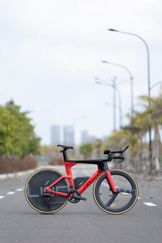 Lún Kronos carbon disc wheel on red time trial bike with tri-spoke front wheel, for track racing.