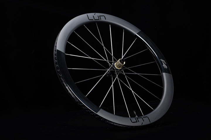 Lún Routte 3 carbon wheel: matte grey, gloss black sections, gold hub, silver spokes.