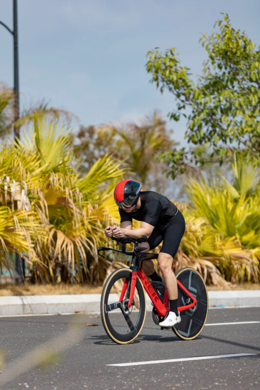 Lún Kronos disc wheel on red time trial bike, matte black carbon fiber with white LÚN logo. For track racing.
