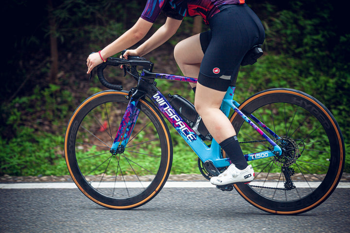 Cyclist riding a road bike with Lún HYPER D45 disc brake carbon wheels, featuring matte black rims and tan wall tires.