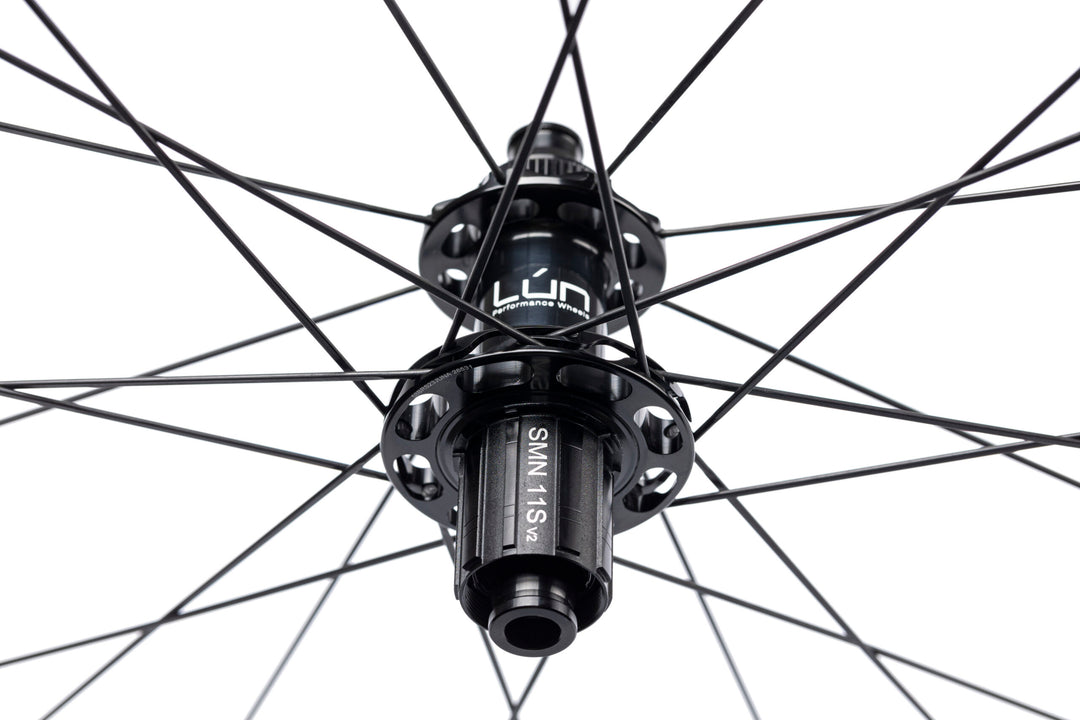 Close-up of Lún Road TD30 rear disc brake hub, matte black, with SMN 11s v2 freehub, bladed spokes, Lún logo.