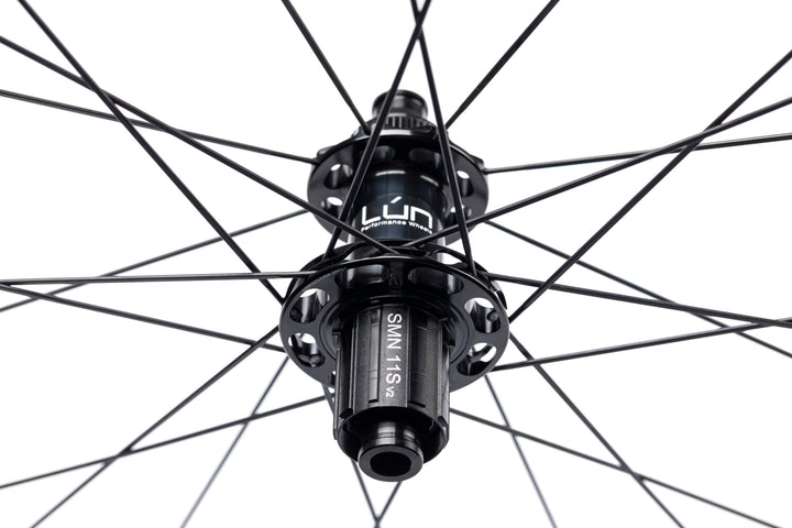 Close-up of Lún Road TD30 rear disc brake hub, matte black, with SMN 11s v2 freehub, bladed spokes, Lún logo.