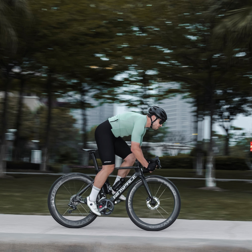 Cyclist riding a road bike with Lún HYPER 23 SE R67 UD carbon wheelset, grey HYPER branding on blurred background.