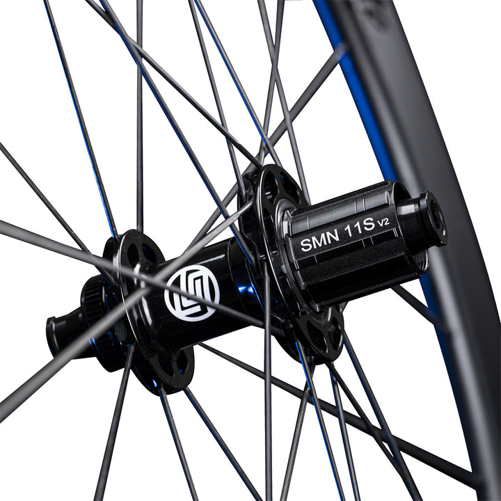 Close-up of Lún Routte SE road bike wheel hub showing black finish, white L logo, SMN 11S V2 freehub, and spokes.
