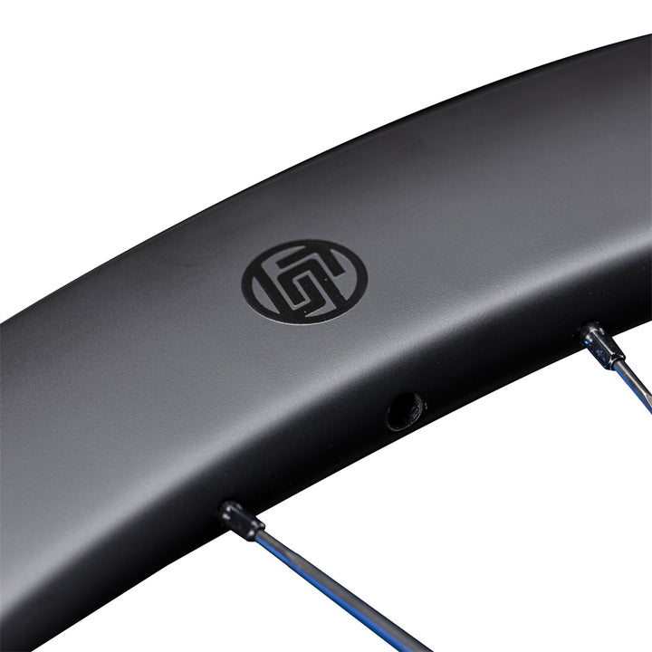 Lún Routte SE 45mm disc brake wheelset carbon rim, matte black with Lún logo and blue spokes. Close-up detail.