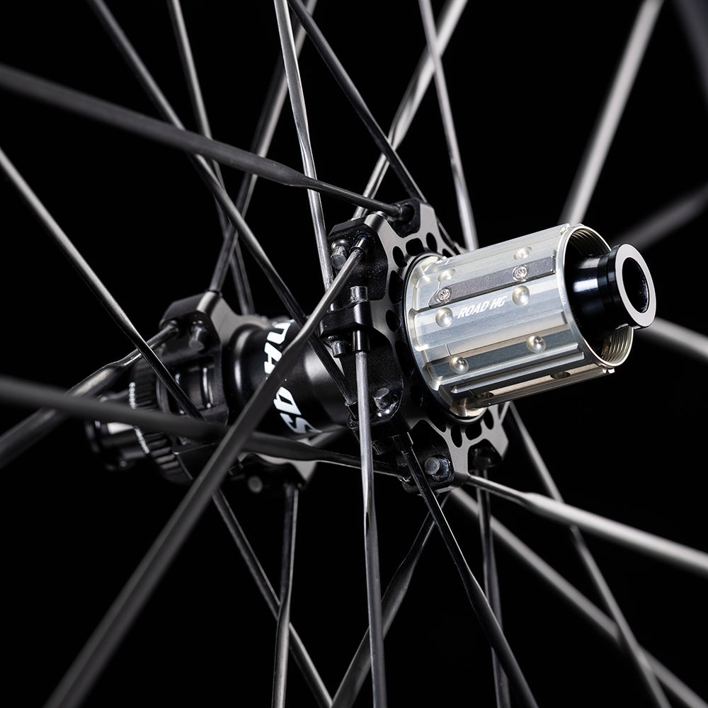 UNAAS Pro D50 rear wheel hub close-up, silver freehub with ROAD HG text, black carbon spokes, on product page.