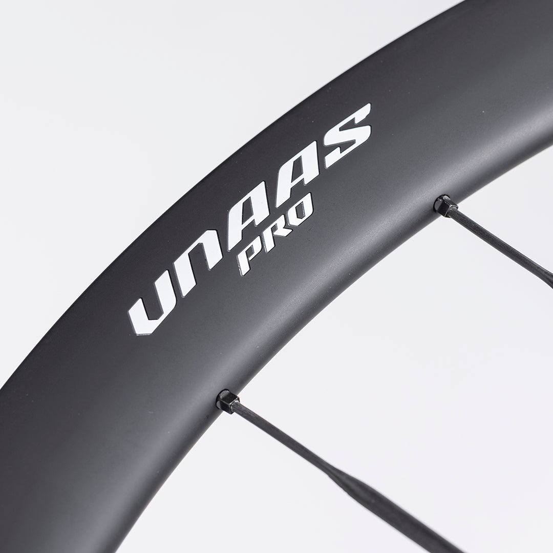 Close-up of UNAAS Pro D40 matte black carbon wheel rim with white branding and carbon spokes.