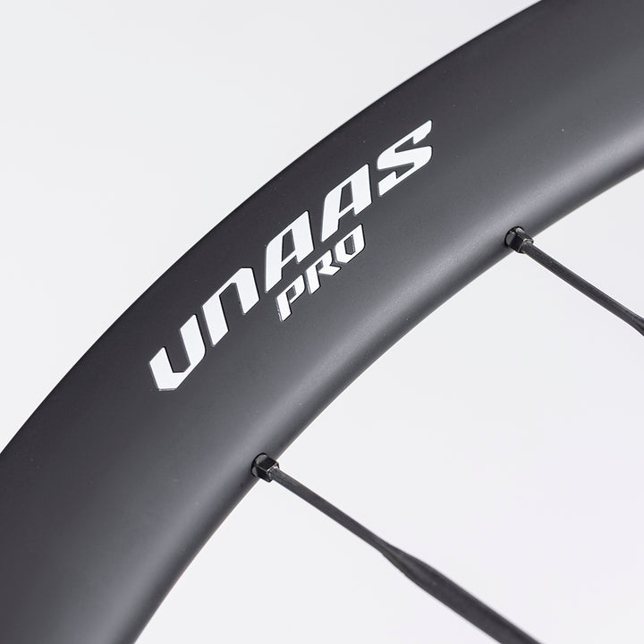 Close-up of UNAAS Pro D40 matte black carbon wheel rim with white branding and carbon spokes.